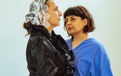 Shooting per lo spettacolo Arte Bella con le due protagoniste Florence Nightingale e Teresa. Entrambe sono in piedi. Florence, girata di lato, guarda a destra. Teresa, vicino a lei, leggermente indietro, guarda Florence.
