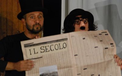 Piano americano dei due protagonisti. Hanno in mano un giornale dietro il quale si nascondono. Lui, a sinistra, ha in testa un cilindro. Lei, a destra, indossa degli occhiali da travestimento, con naso e baffi finti, e una bombetta.