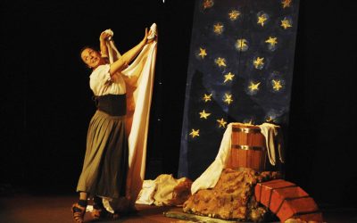 La lavandaia stende il lenzuolo lavato. Accanto a lei la scenografia: una roccia con sopra la botte con l'acqua per lavare i panni, e dietro un tendone blu con stelle dorate rappresentante il cielo stellato.